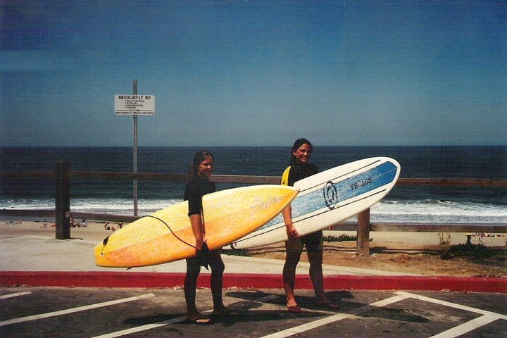 Two surfers holding their boards